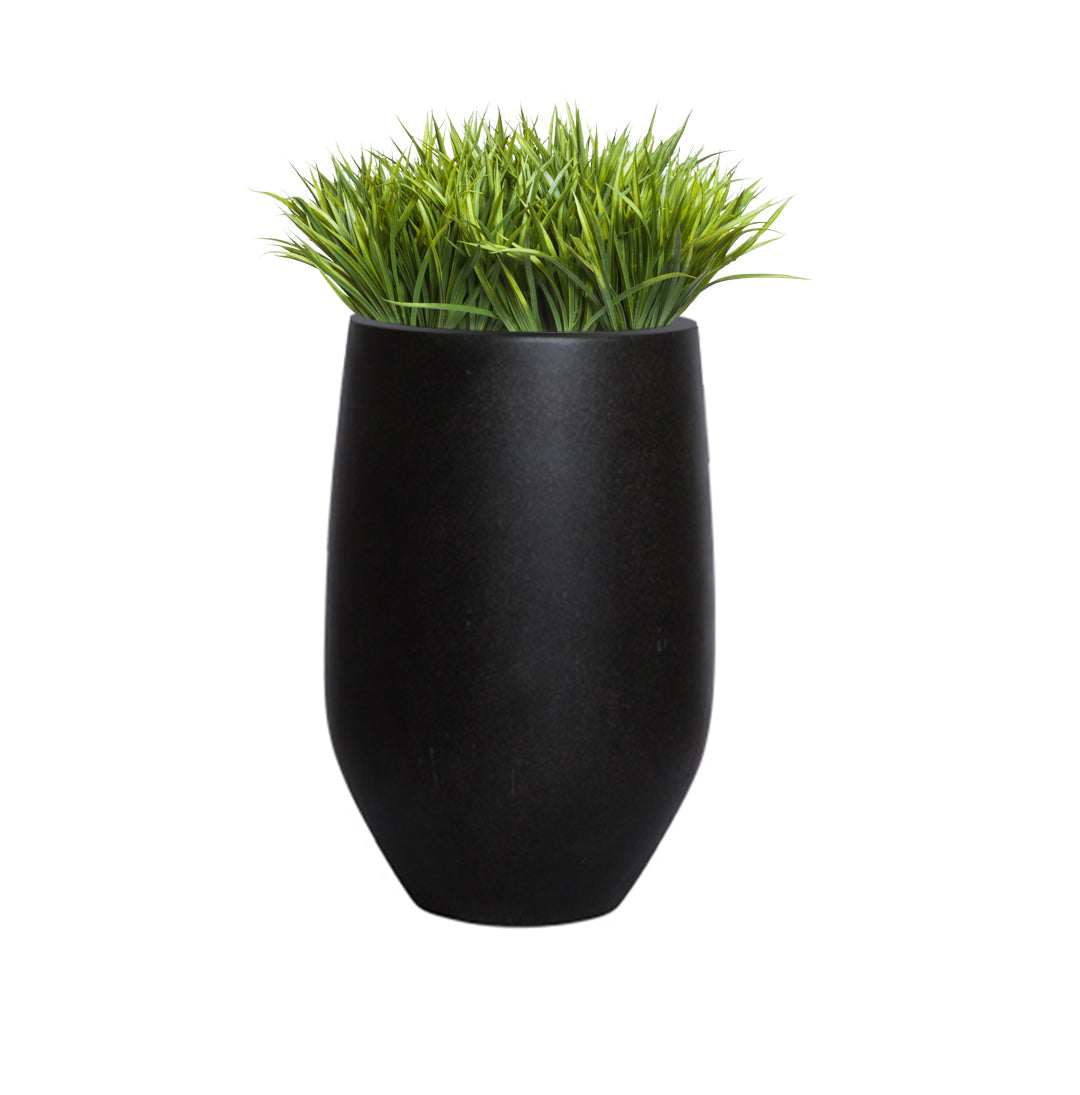 Artificial sword grass in modern black planter on white background