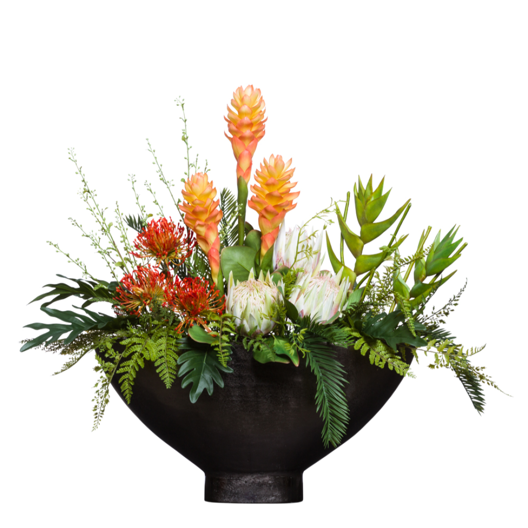 Artificial tropical flower arrangement with protea, ginger, and lush greenery in black bowl