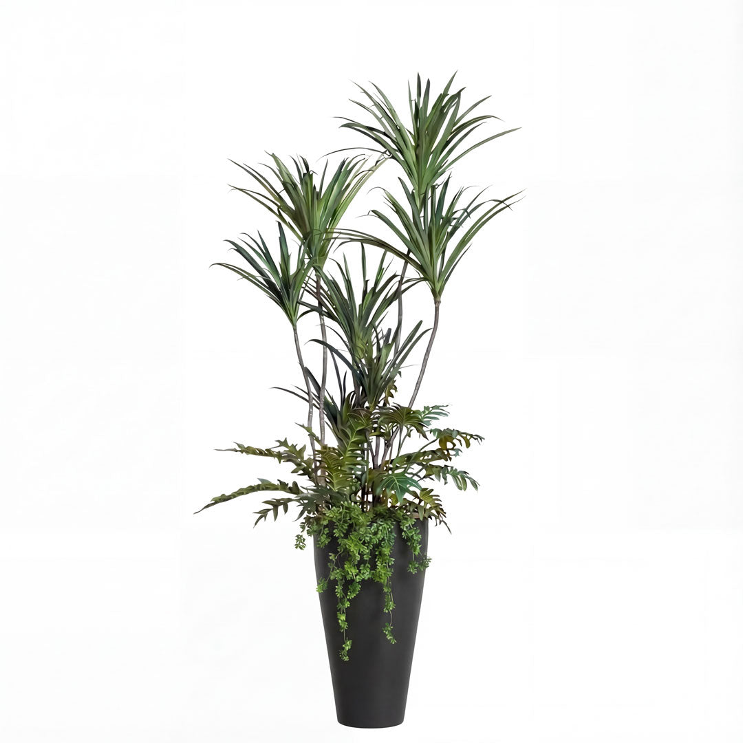Artificial dracaena plant with mixed greenery in tall black planter on white background